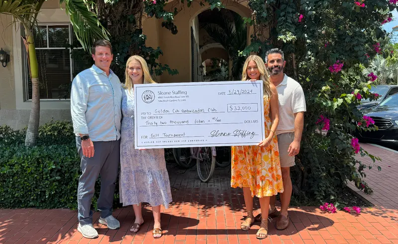 Four people hold a Sloane Staffing check for $32,000 payable to the Golden Cub Ambassadors Club for a golf tournament.
