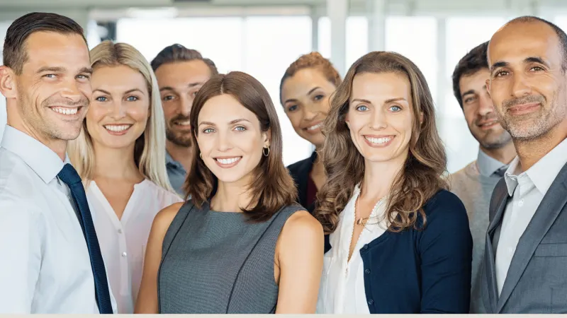 A diverse group of professionals smiling and posing for the camera in business attire.