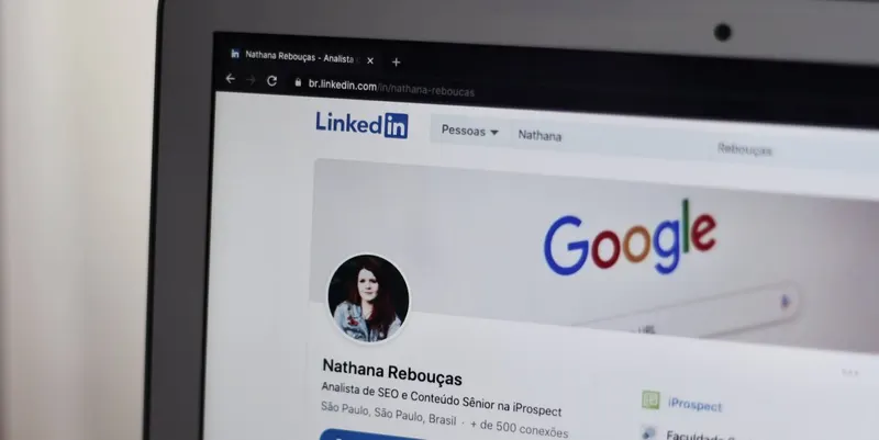 Laptop screen showing the LinkedIn profile of Nathana Rebouças, an SEO analyst; the Google logo is also visible.