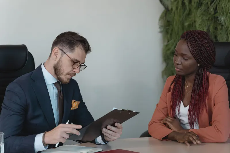 A person on a phone call at a desk taking notes on a laptop, mid-conversation.