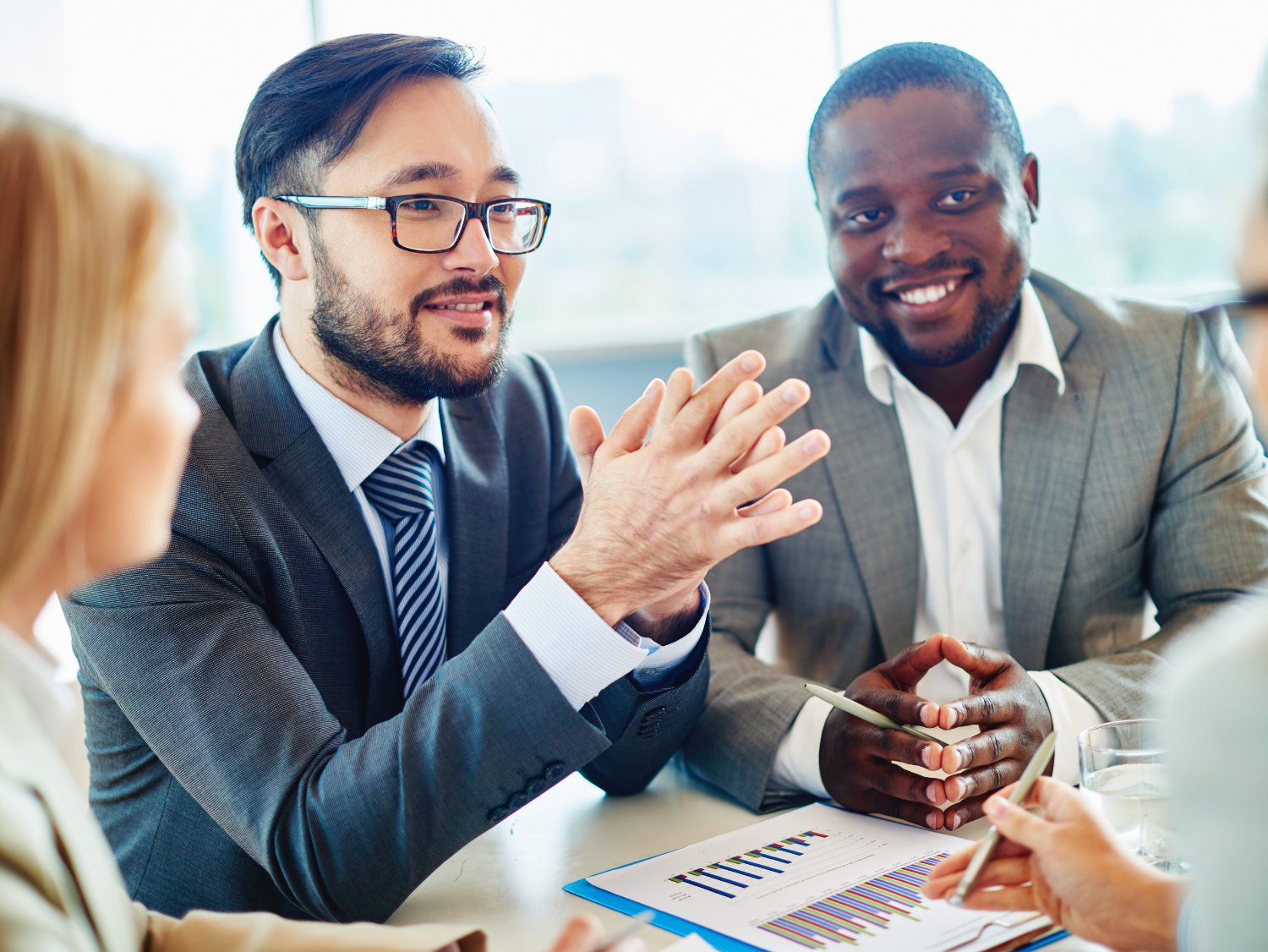 Three business professionals in suits gathered around a table, discussing a report.