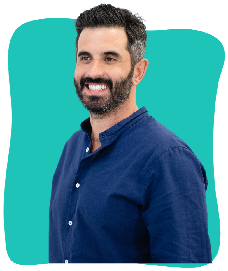 A smiling man with dark hair and a beard, wearing a navy blue button-down shirt with a stand-up collar, looking to the left.