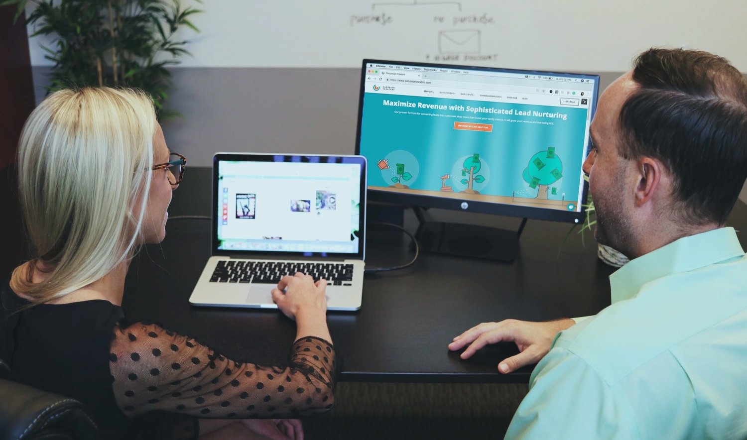 A woman and man looking at computer screens displaying marketing graphics and text about maximizing revenue.